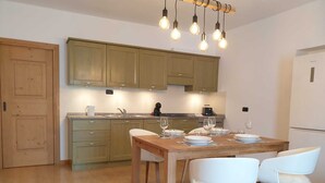 Una cocina moderna con armarios de madera, una mesa de comedor preparada para cuatro personas y un horno empotrado.