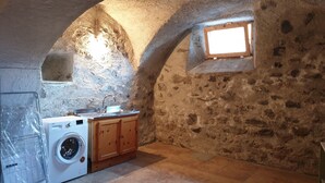 Una cocina rústica con lavadora, armarios de madera y un ventanal pequeño.