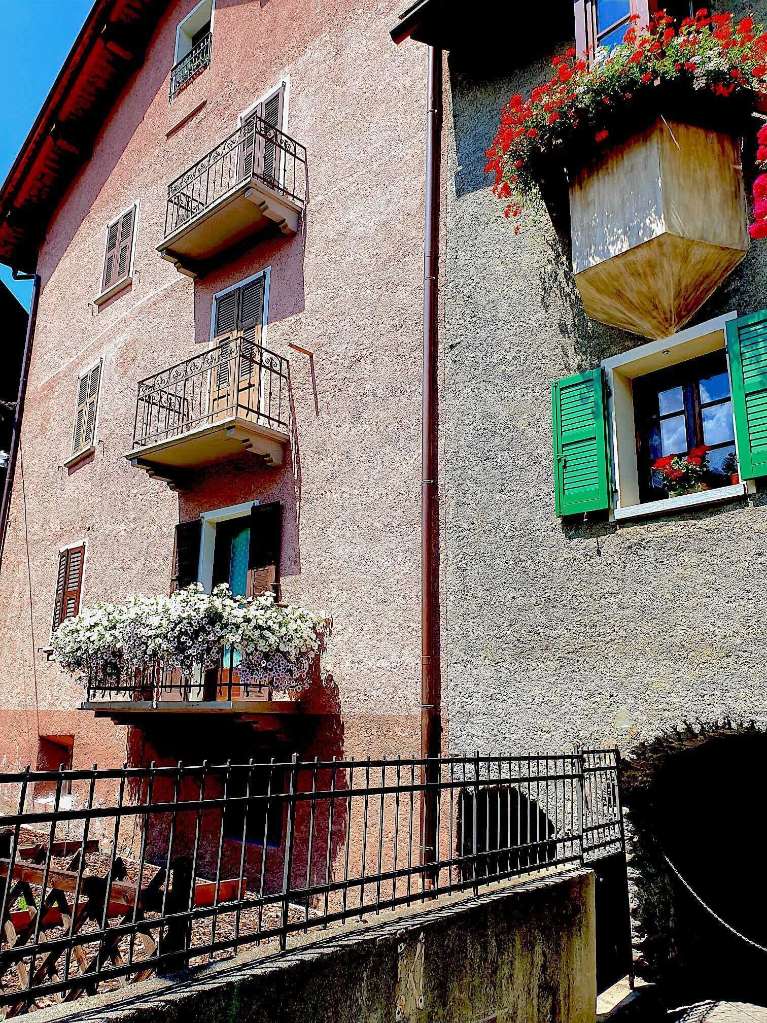 A building with balconies, flower boxes, and a metal fence.