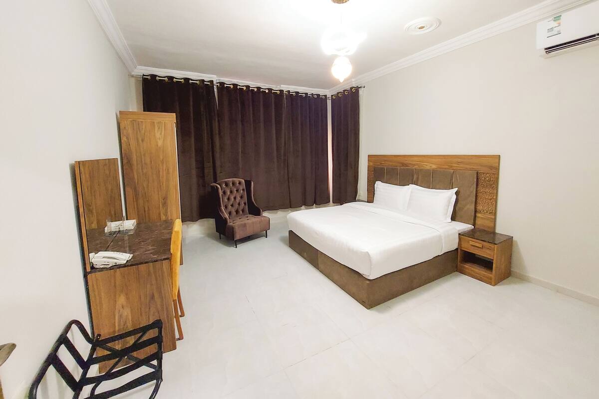 Una habitación de hotel con cama, escritorio, silla y armario.