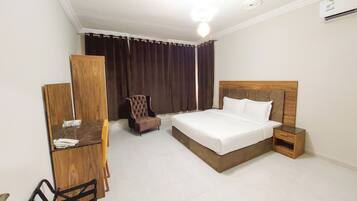 Una habitación de hotel con cama, escritorio, silla y armario.
