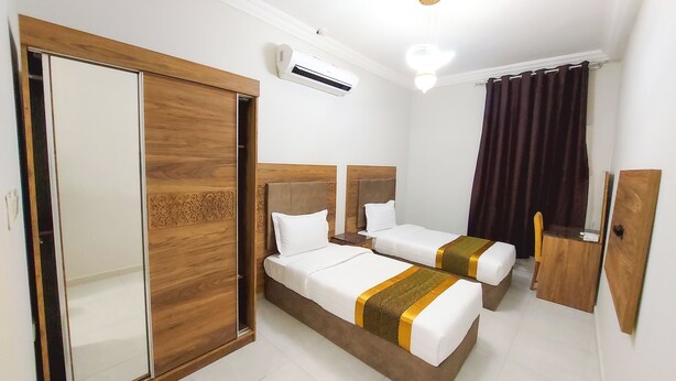 Une chambre d’hôtel avec deux lits, une armoire, un appareil de climatisation et un miroir.