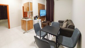 Un espace de vie compact comprenant une kitchenette, un coin repas et un téléviseur.