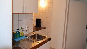 A kitchen with a double sink, a coffee maker, and a bottle of dish soap.