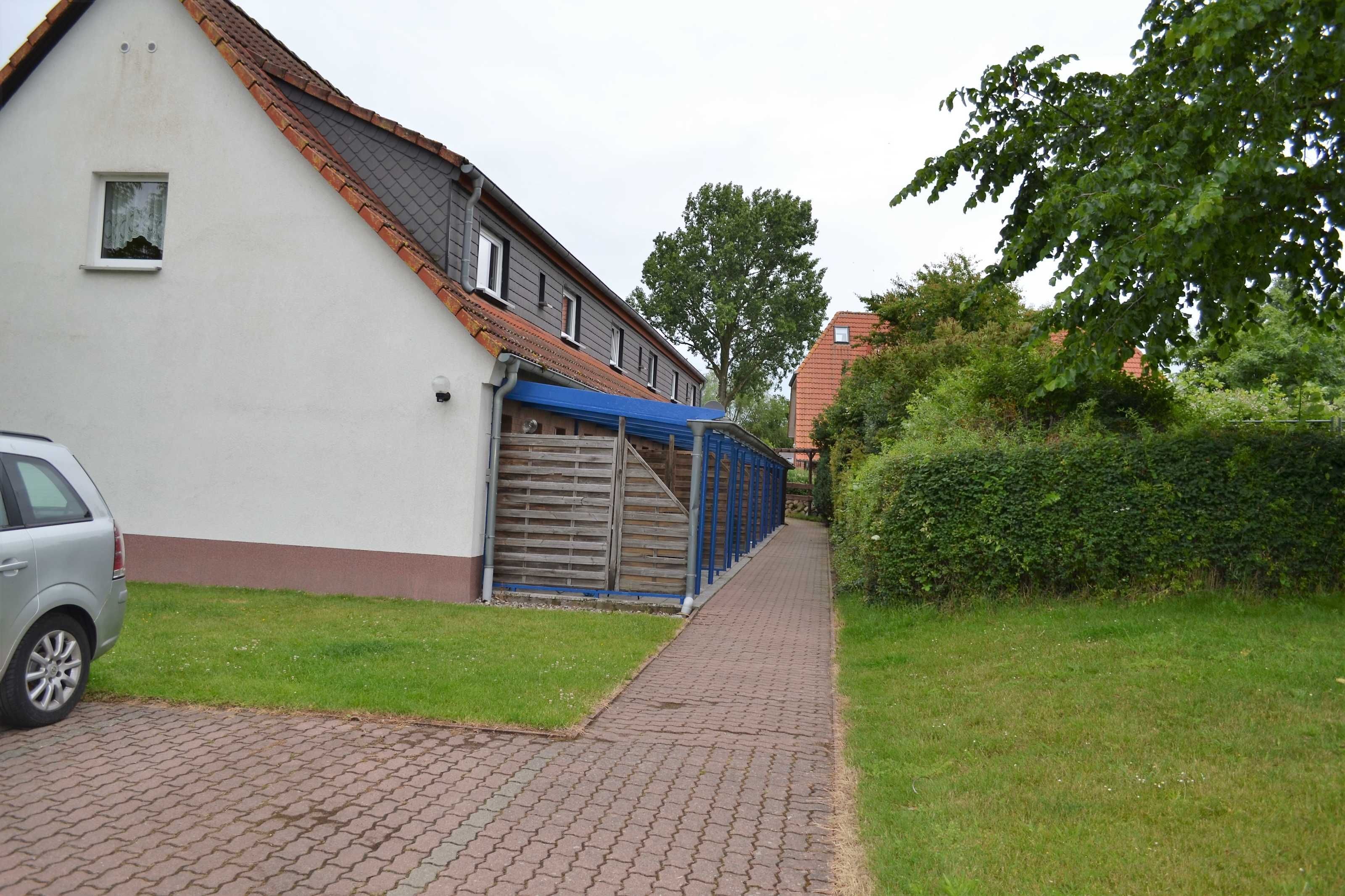 Un immeuble résidentiel avec un chemin pavé, un garage et une voiture garée sur le côté.