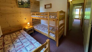 A bunk bed room with a wooden wall, a nightstand with a lamp, and a painting.