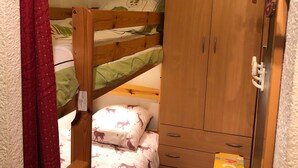 A bunk bed with a wooden wardrobe below, a small table, and a curtain. - Studio with Cabin at the Foot of the Slopes, Pets Allowed (Les Menuires)