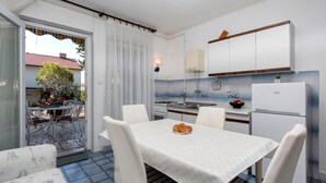 Une cuisine moderne avec des meubles blancs, un réfrigérateur blanc et un coin repas comprenant une table et des chaises.