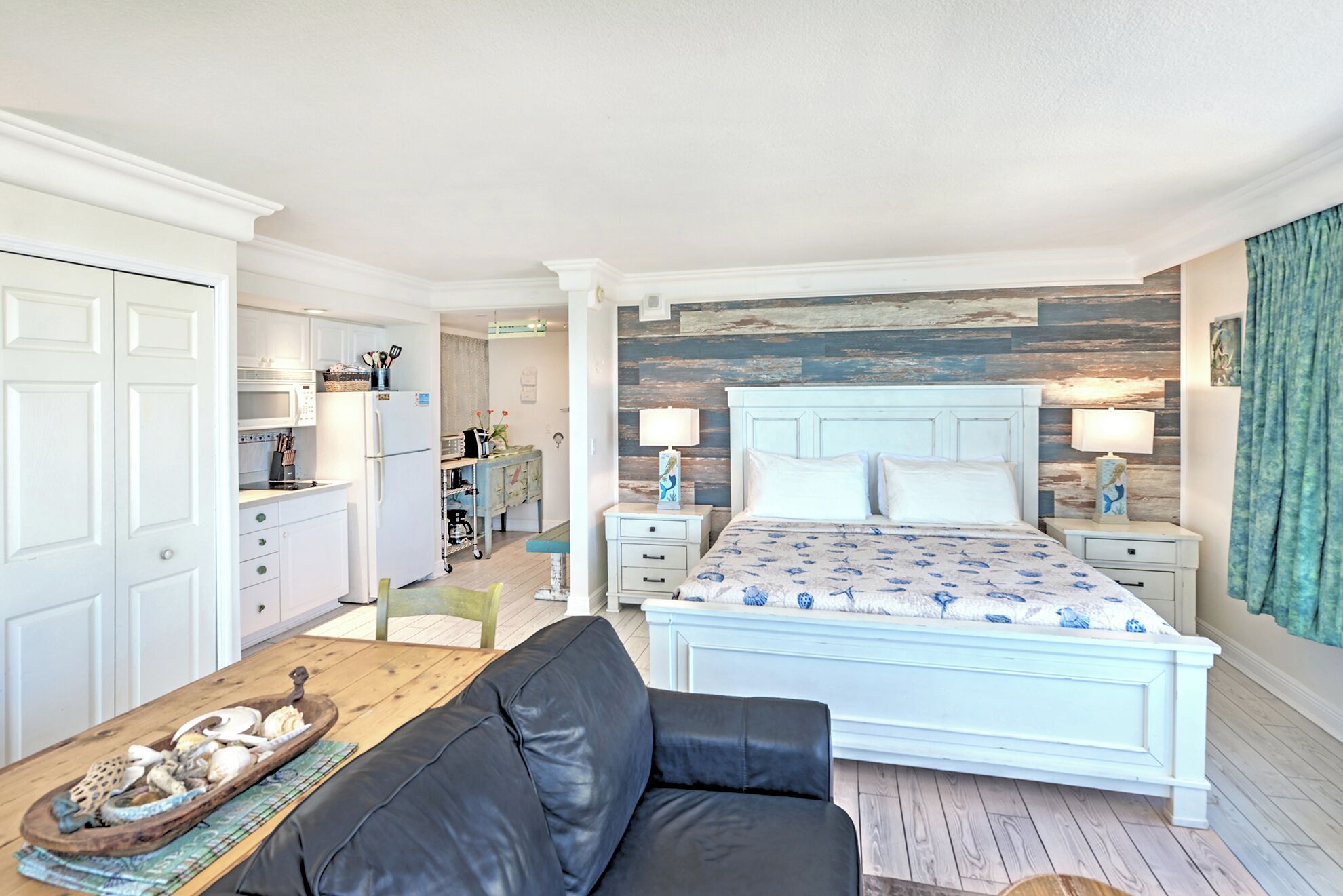 Une chambre à coucher comprenant un lit, des tables de chevet, une commode, une table basse en bois et un canapé en cuir noir.