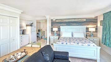 Une chambre à coucher comprenant un lit, des tables de chevet, une commode, une table basse en bois et un canapé en cuir noir.