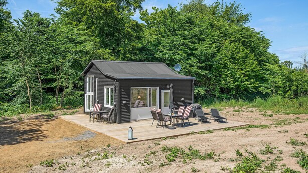 Une petite cabane dotée d’une terrasse et de meubles de jardin.