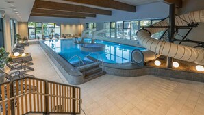 A modern indoor swimming pool with a slide, seating areas, and a staircase leading to an upper level. - Gorgeous home in Lembruch/Dümmer See (Lembruch/Dümmer See)