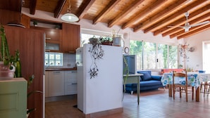 A spacious kitchen with wooden cabinets, a white refrigerator, and a dining area with a table and chairs. - Villa Bruffalori (Scicli)