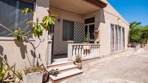 A house with a covered porch, a small garden, and a clear blue sky. - Villa Bruffalori (Scicli)