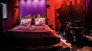 Een slaapkamer met een bed, een raam, dakraam en een bad.