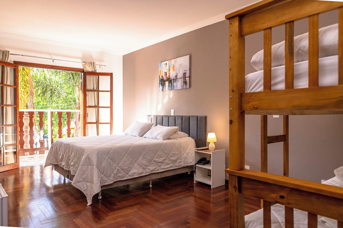 Un dormitorio con cama, mesita de noche y vistas a la vegetación a través de una ventana.