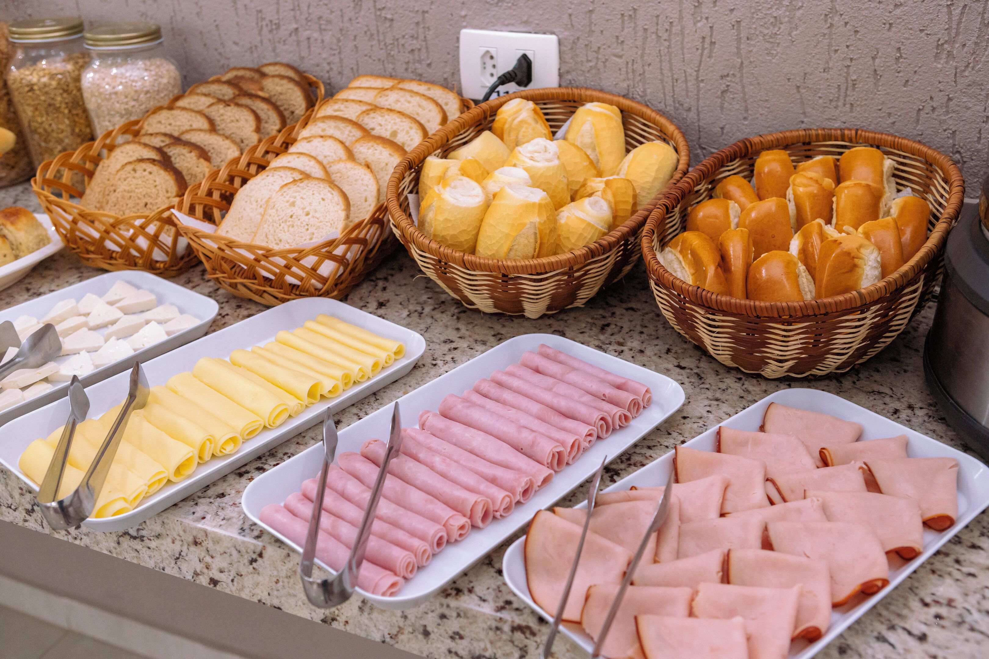 Un bufé con diversos alimentos, incluyendo pan, queso y embutidos.