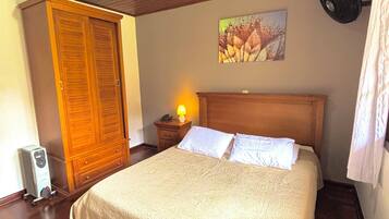 Une chambre avec un plafond en bois, un lit avec une literie blanche, une table de chevet avec une lampe et un tableau au mur.