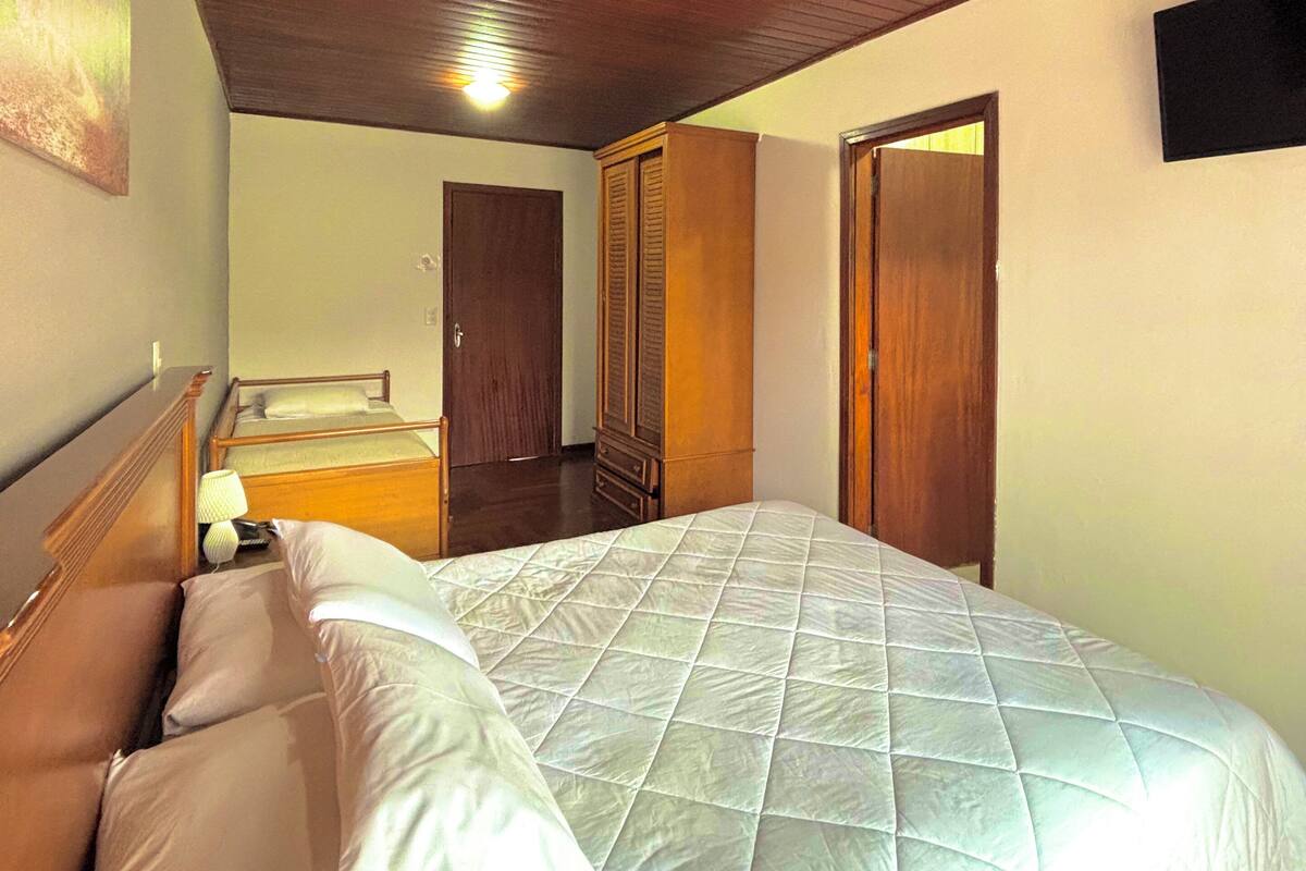 Un dormitorio con una cama grande, techo de madera y un armario.