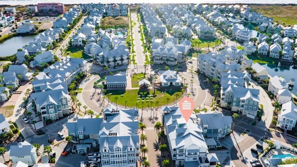 A coastal residential area with uniform houses, a central road, and a body of water in the background.