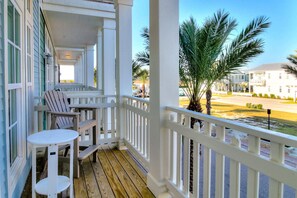A wooden deck with a white railing, a table, and two Adirondack chairs. - Luxe, 4-Story Penthouse@Cinnamon Shore near Town Center & More Amenities! (Port Aransas)