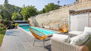 Una piscina con dos sillas de mimbre y un sofá blanco.