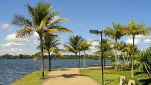 A pathway leading to a beach with palm trees and a bench. - Flat Saint Moritz - Centro de Brasília (Brasília)