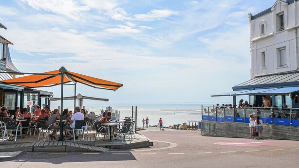 Un restaurant en bord de mer avec une terrasse et vue sur la plage.