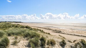 Une plage avec des dunes et une vaste étendue de sable.