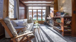 A cozy living room with a sofa, a glass coffee table, and a bookshelf filled with books.