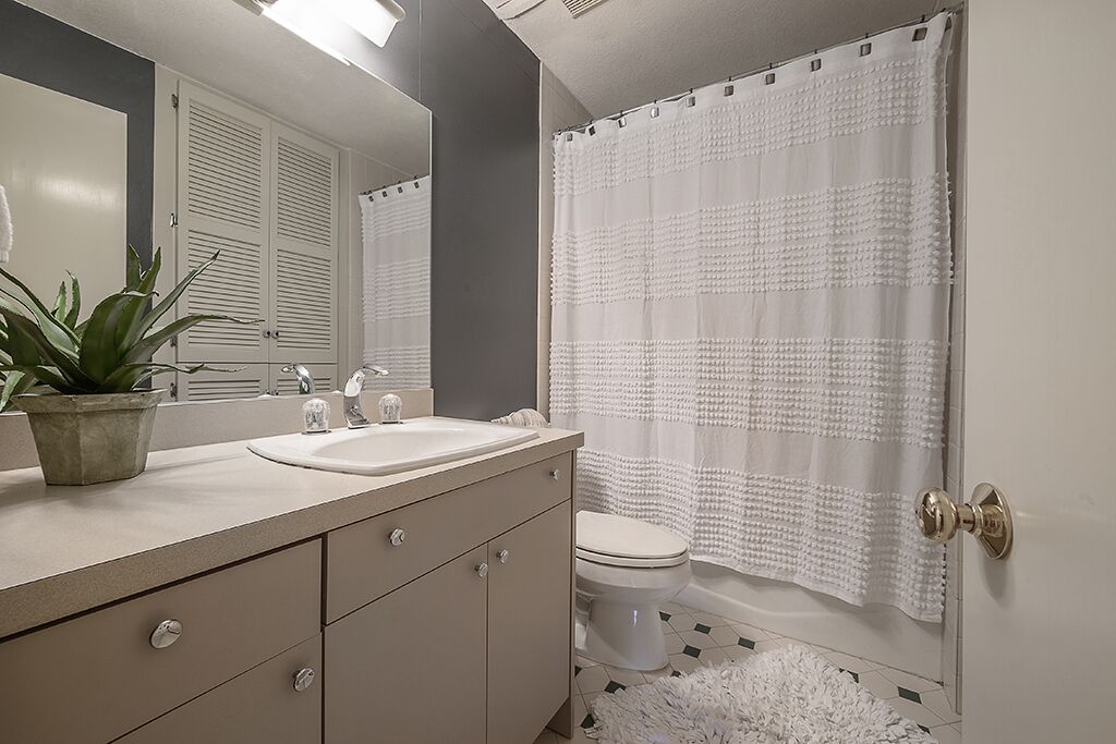 Un baño con lavamanos, espejo e inodoro.