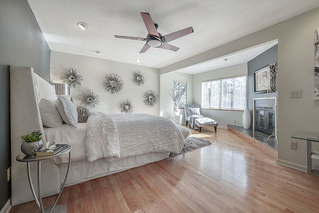 A modern bedroom with a large bed, a ceiling fan, and decorative wall art.