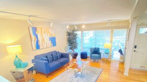 A modern living room with a blue sofa, a coffee table, and a patterned rug. - Spacious House with heated 24ft swim spa pool (Tampa)
