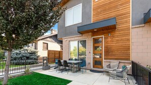 Une maison moderne dotée d’un patio, d’un coin repas et d’un petit jardin.