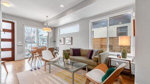 Un salon moderne avec une table basse en verre, un canapé et un coin repas avec des chaises.