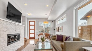 Un salon moderne avec une cheminée, une table basse en verre, un canapé et un téléviseur fixé au mur.