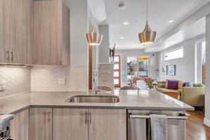 Una cocina moderna con una isla central, electrodomésticos de acero inoxidable e iluminación colgante.