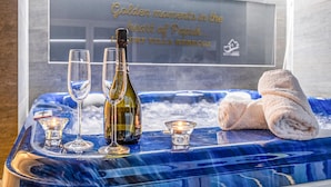 A spa tub with a blue marble design, a bottle of wine, two glasses, and a towel.
