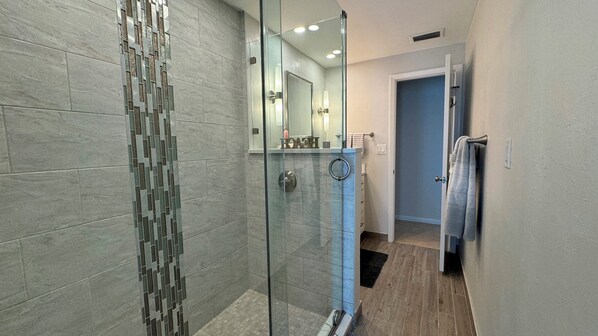 A modern bathroom with a glass shower enclosure, a visible towel rack, and a mirror.