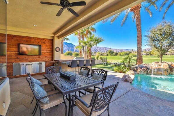 An outdoor patio with a pool, dining area, and mountain views.