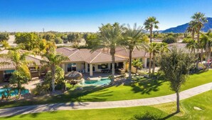 A residential property with a swimming pool, multiple palm trees, and a mountain in the background. - PGA West, private pool and spa outdoor covered TV (La Quinta)