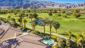A resort with a pool, palm trees, and a mountain backdrop. - PGA West, private pool and spa outdoor covered TV (La Quinta)