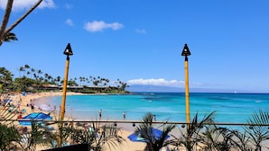 A beach with clear turquoise water, palm trees, and a view of the ocean.