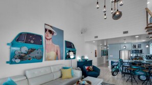 Ein modernes Wohnzimmer mit einer Couch, einem Couchtisch und einem Essbereich mit einem türkisblauen Tisch und Stühlen.