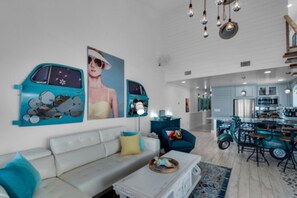 A modern living room with a sofa, a coffee table, and a dining area with a teal table and chairs. - SPECTACULAR, TOTALLY RENOVATED 3 BEDROOM + CONDO ON BEACH, GORGEOUS GULF VIEWS  (Miramar Beach)