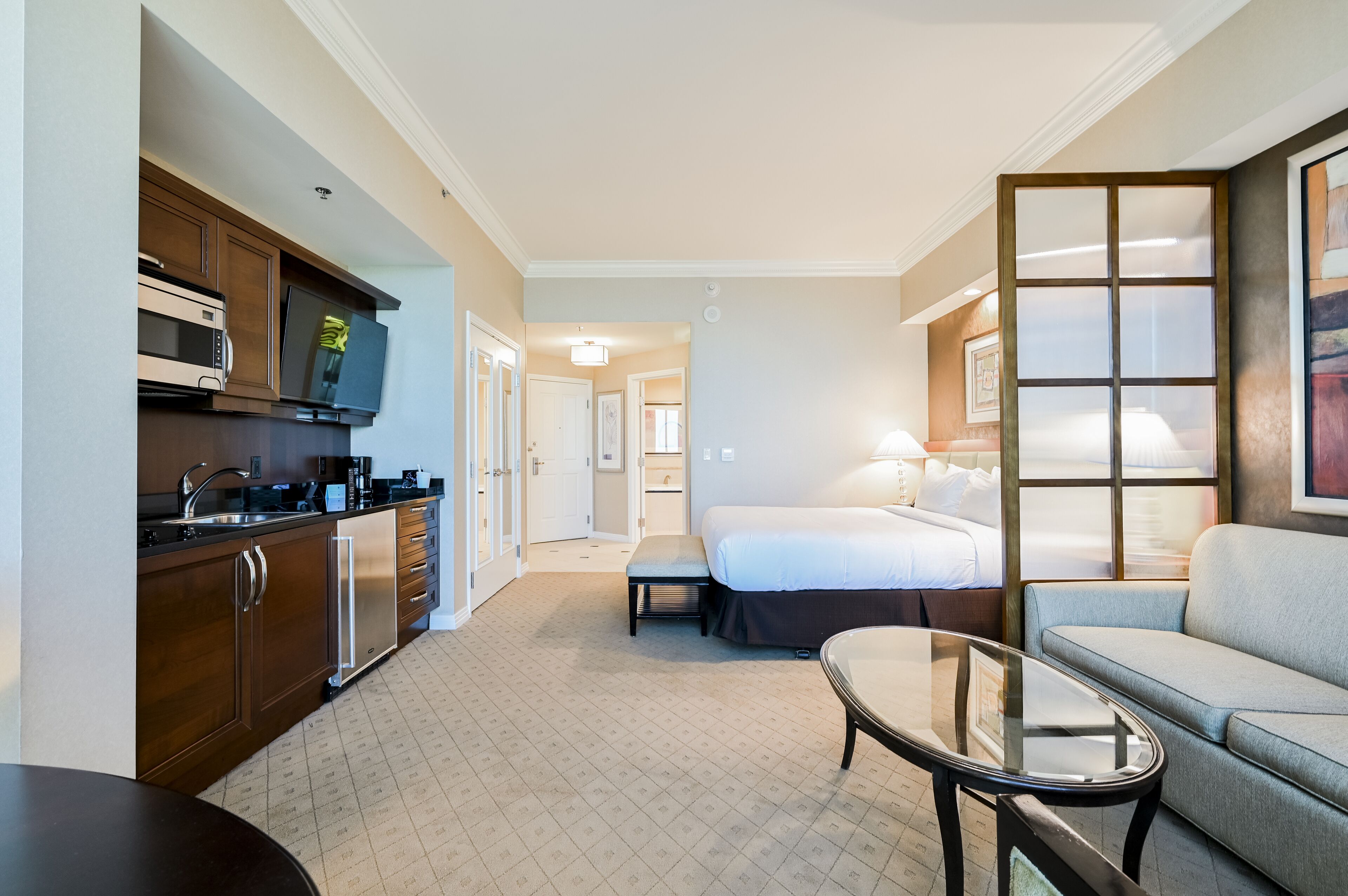 Una habitación de hotel con kitchenette, una cama, un espacio de descanso y un ventanal grande.