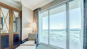 A hotel room with a large sliding glass door to a balcony, a cushioned bench, and a lamp. - StripViewSuites Two Bedroom at Signature (Las Vegas)