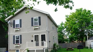 A two-story house with a front porch, a satellite dish, and a fenced backyard. - Atlantic Street Guesthouse - The Best Kept Secret! (Newport)