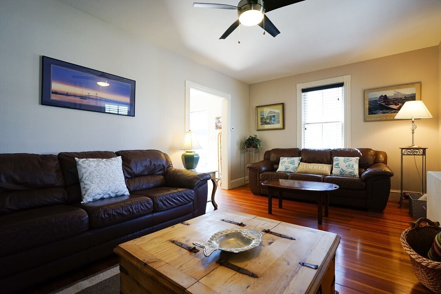 A living room with two leather sofas, a wooden coffee table, and a ceiling fan.