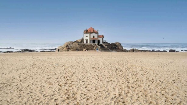 A beach with a small building on a rock, featuring a staircase leading to the entrance. - HostWise - Seaside Beach Flat (Vila Nova de Gaia)
